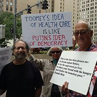 Toomey protestor carrying sign "Toomey's idea of healthcare is like Putin's idea of democracy" via @lisajwardle | Twitter