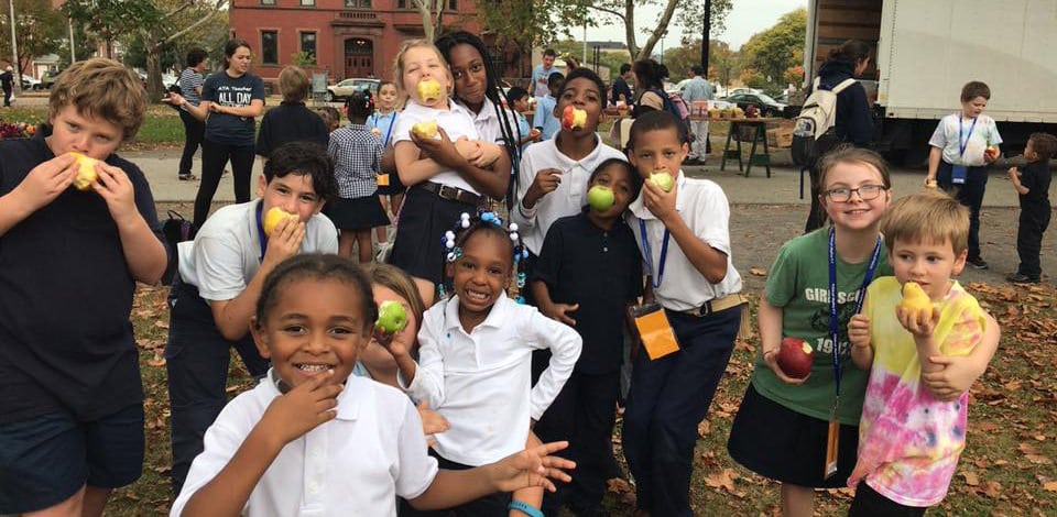 Kids of Allegheny Traditional Academy eat apples at the North Side farmers market, Oct. 2017