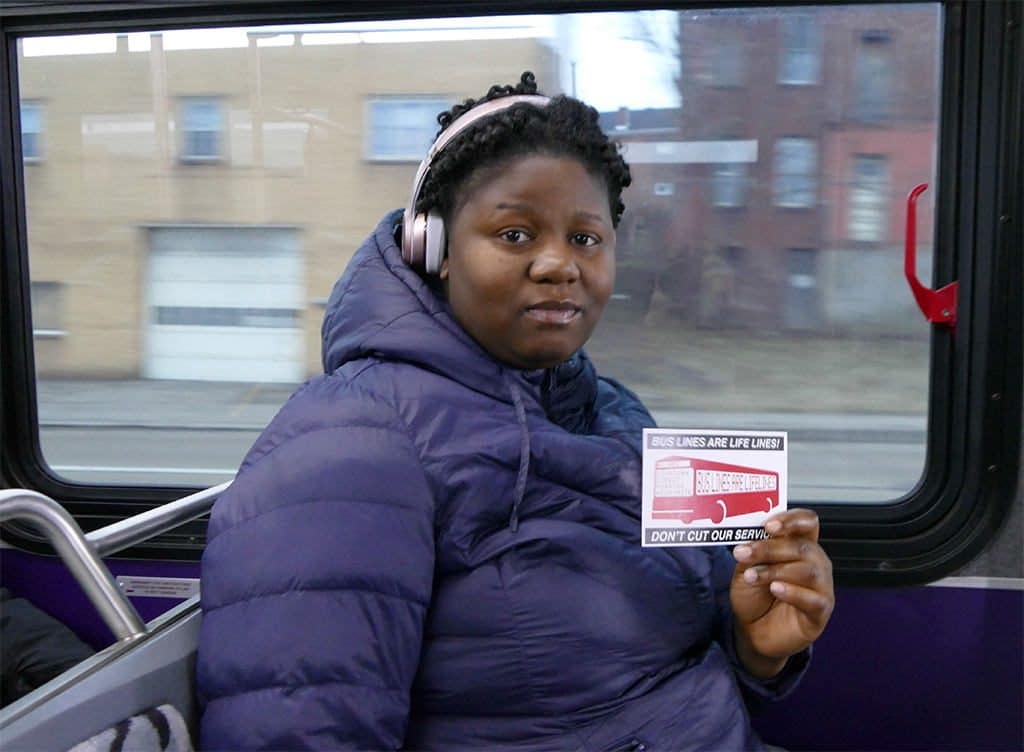 61ABC bus rider holding "bus lines are lifelines" card