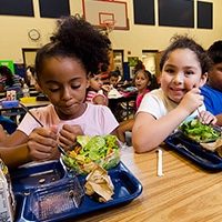 elementary school children eat lunch in cafeteria