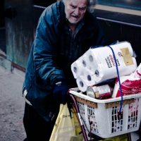 older man pushing groceries (via Flickr/Christos Tsirbas)