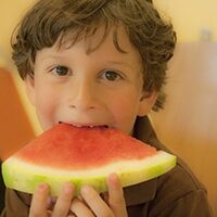 Kid eating watermelon via Flickr/Riley Kaminer